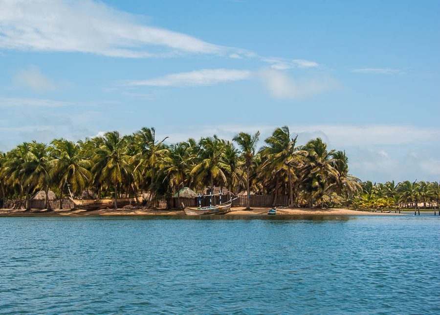 Ada Foah beach at sunset, thatched huts along the shore